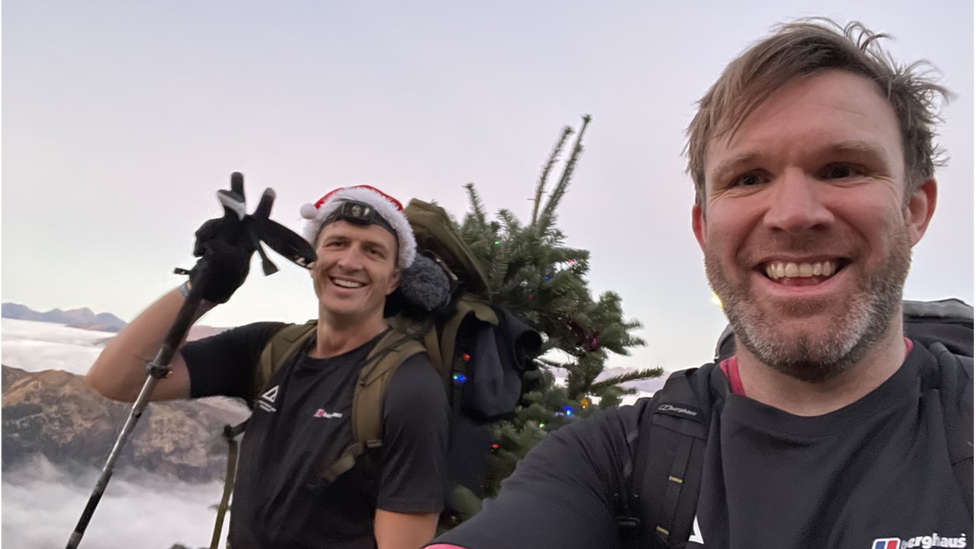 Ed Jackson and Ross Stirling on part of their climb. They are both smiling. Ed is wearing a Santa hat.