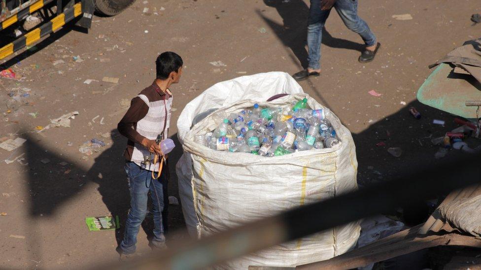 Man looking into bag of bottles in Dharavi