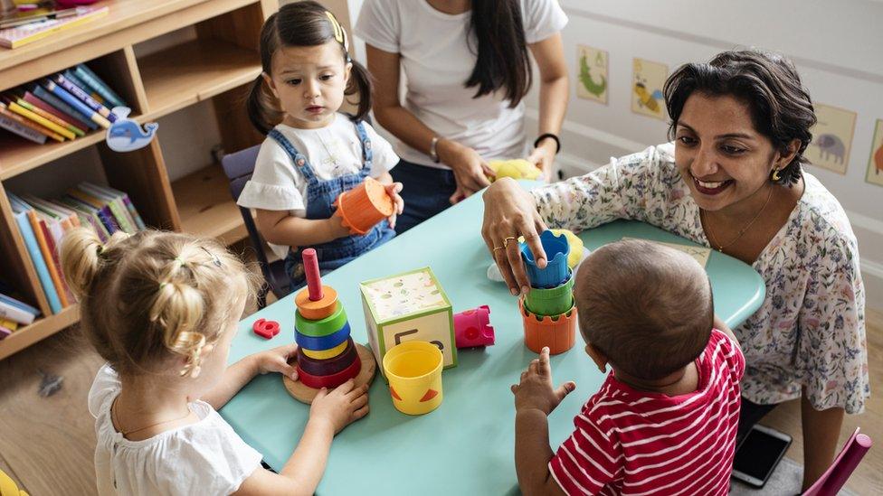 Young children playing with a teacher in a nursery