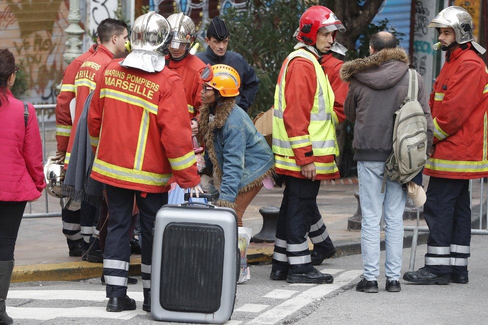 Firefighters and police evacuate people from the street where buildings collapsed in Marseille, 7 November