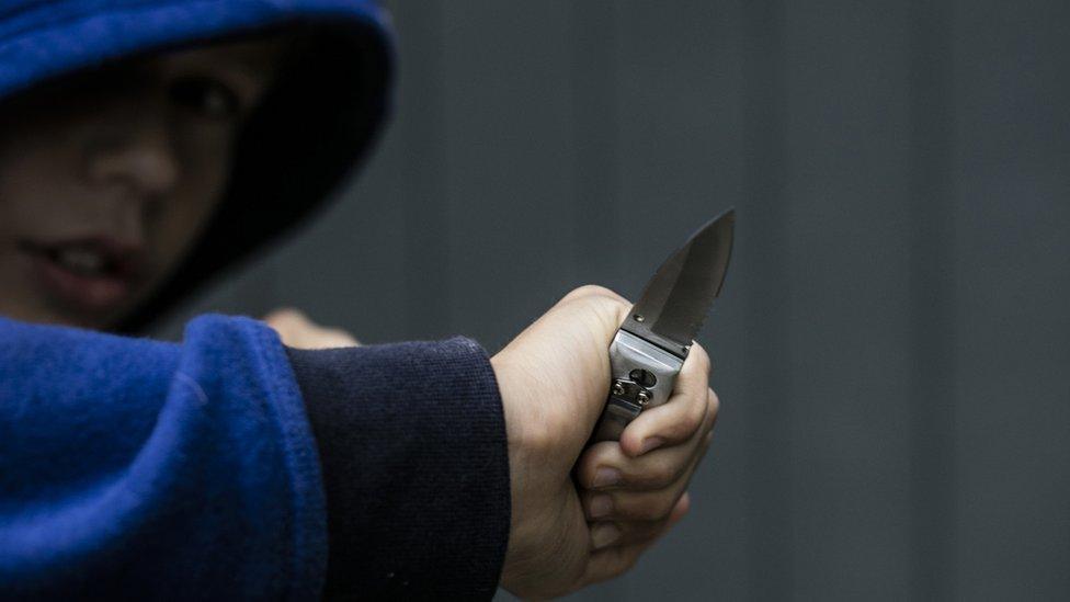 Staged photo of a young man holding a knife