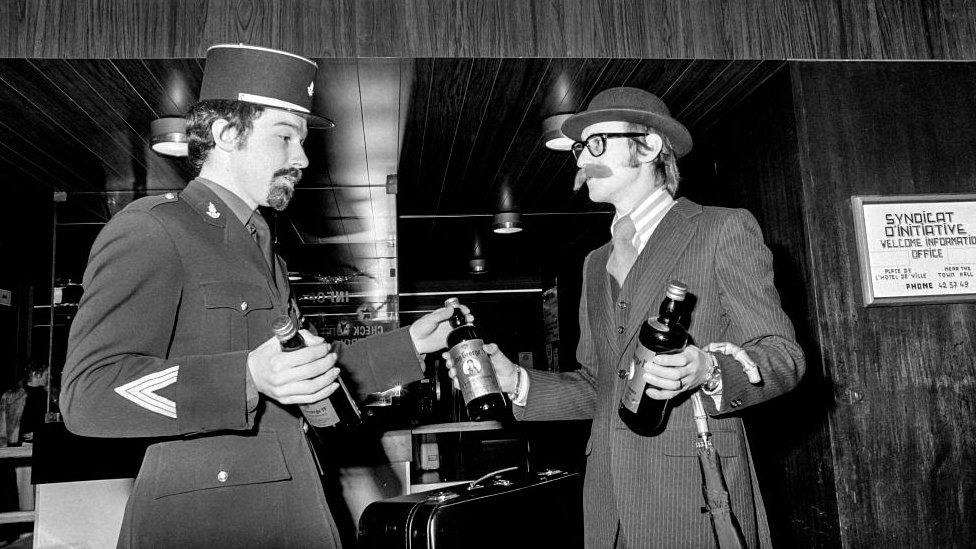 A British man offers a bottle of whisky to a customs officer from Le Havre