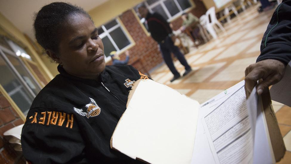 Iris Mendoza and Pedro Carreño flip through Mr Pedro Carreño's medical files in a Venezuelan migrant refuge in Lima, Peru on July 17, 2019. Pedro Carreño was diagnosed with cancer in Venezuela and the two fled to Peru for treatment.