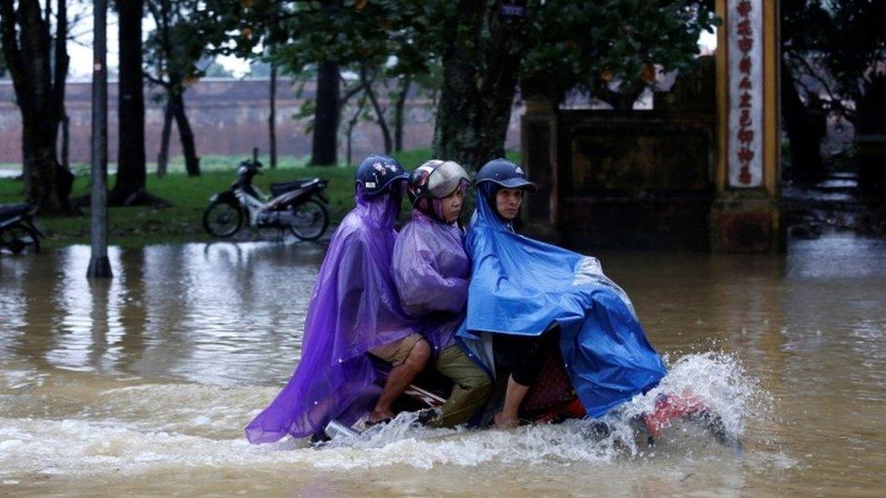 People ride a motorcycle along a flooded road after Typhoon Damrey hits Vietnam (04 November 2017)