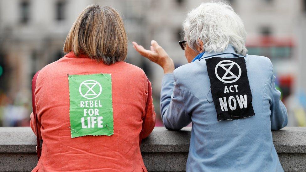 2 female protesters wearing XR signs on their backs