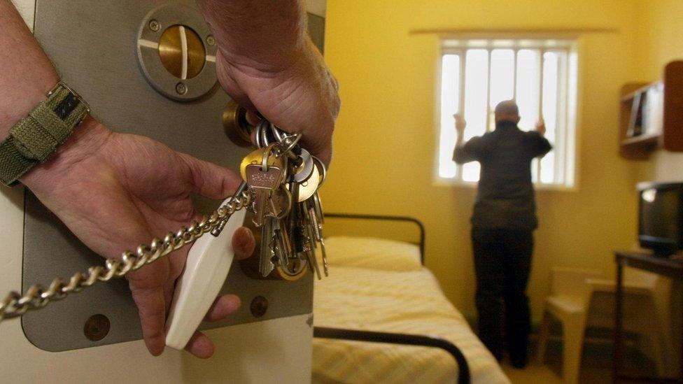 A man in a prison cell with someone locking the door