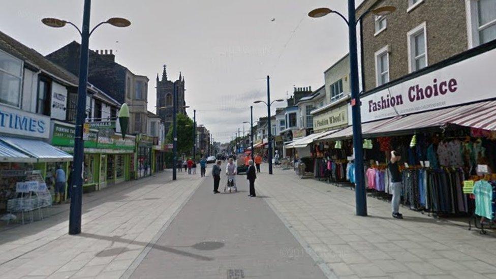 Pedestrianised shopping street with a variety of shops on either side.