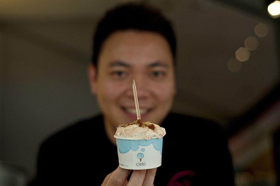 In this picture taken 28 February 2015 owner of Cielo Dolci cafe poses with a cup of Nasi Lemak ice-cream at his cafe in Kuala Lumpur