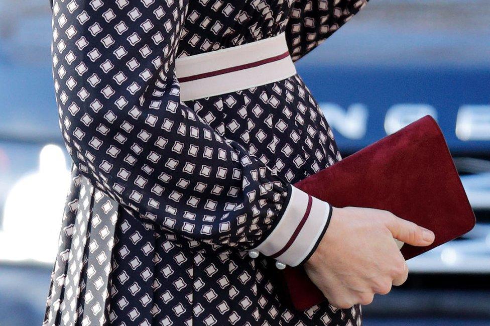 Duchess of Cambridge clasps a Kate Spade bag against her baby bump in November 2017