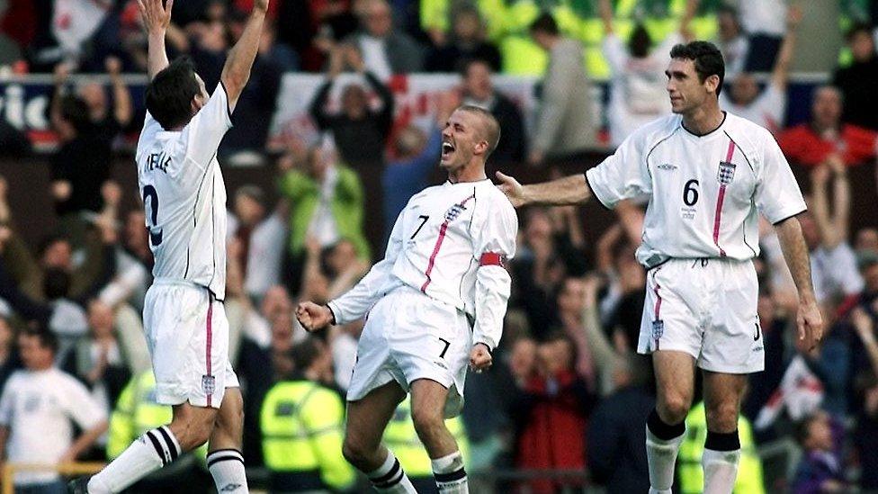 England's David Beckham (C) celebrates with Gary Neville (L) and Martin Keown (R) after scoring an injury-time equaliser against Greece during the World Cup qualifying match at Old Trafford in Manchester 06 October 2001. Beckham ensured England qualified for the World Cup finals with his late goal which salvaged a 2-2 draw to put England top of their group.