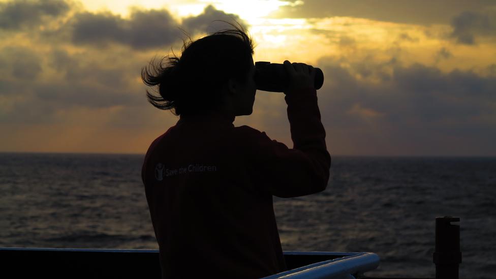 Volunteer looks out to sea through binoculars