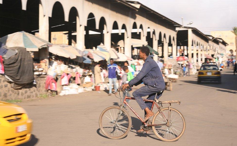 A man cycling past a market in Asmara, Eritrea