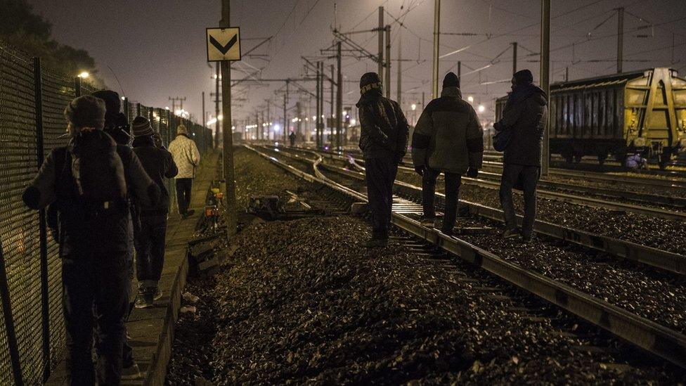 Migrants walk along railway tracks in Calais