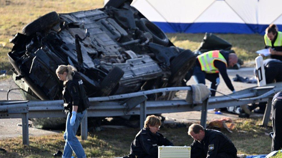 Rescue workers and police officers stand by the overturned vehicle near Ampfing