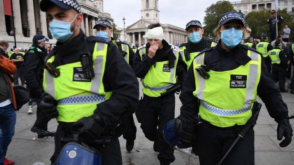 A injured policeman is helped away after police clashes with demonstrators during a "We Do Not Consent" rally in London