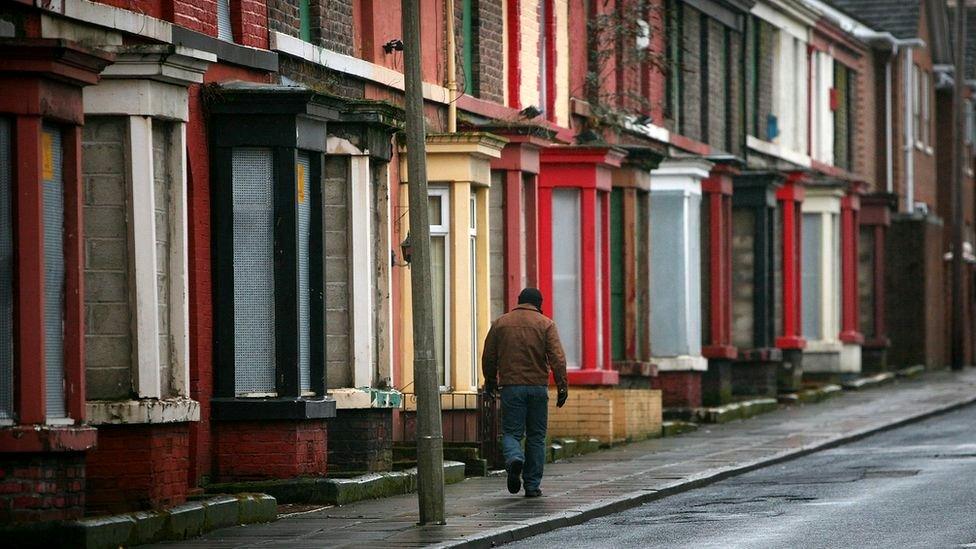 Man walking beside derelict homes