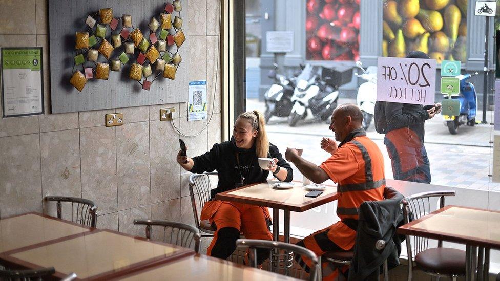 A customer takes a selfie as she sits at a table