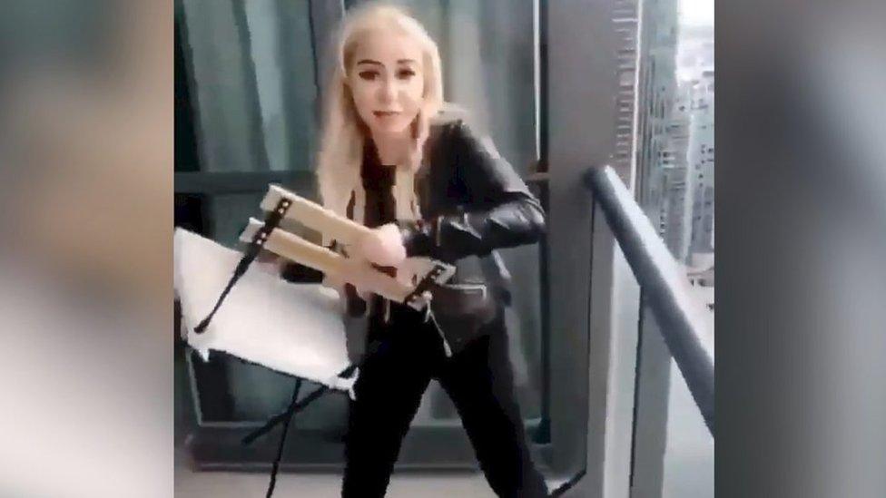 Woman throwing chair from high-rise balcony (grab from video, 12 Feb)