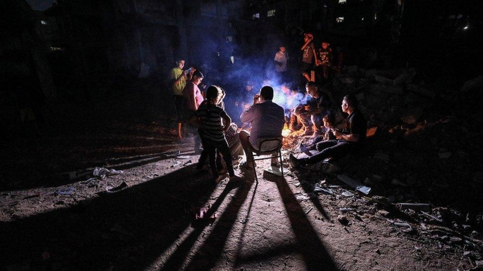 Palestinians whose homes were destroyed sit around a fire - 26 May