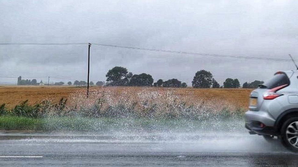 A car driving through the rain at Ramsey Saint Mary's, Cambridgeshire