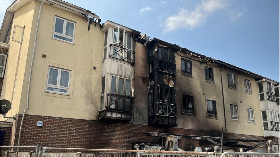 A block of flats with the exterior blackened by fire and smoke