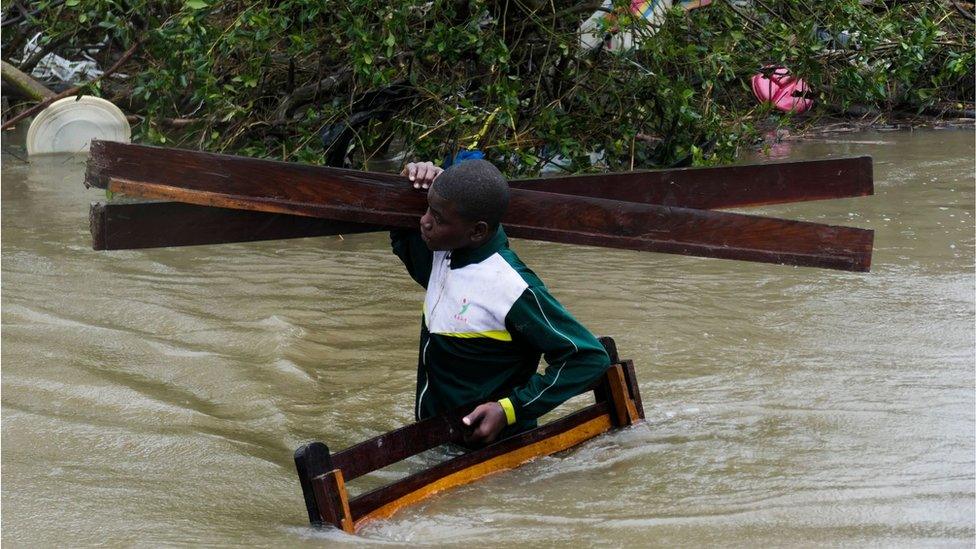 A man collects some wood on a flooded street near Quelimane, as the storm Freddy hits Mozambique, 12 March 2023