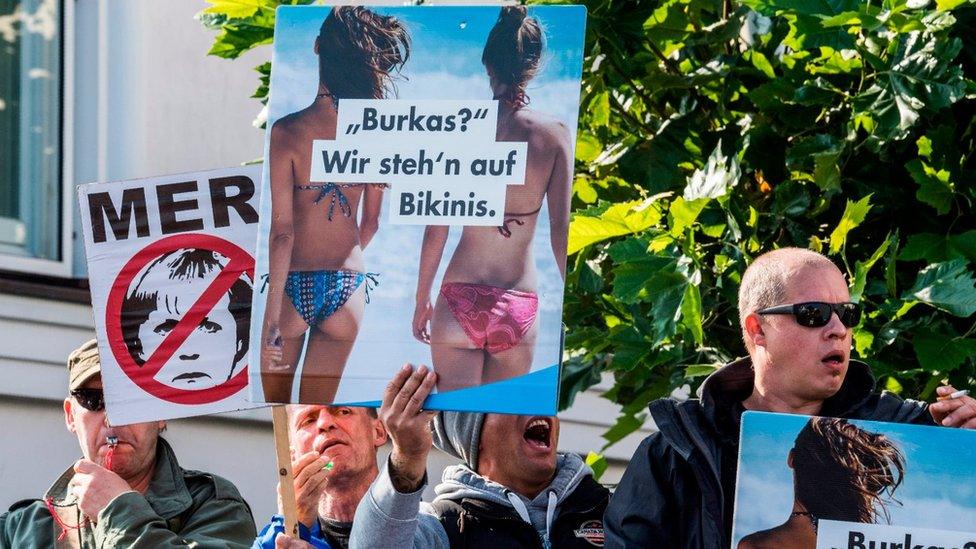 Members of the far-right Alternative for Germany (AfD) display placards as Angela Merkel (unseen) arrived for an election rally at her constituency's Baltic Sea resort of Binz on September 16, 2017