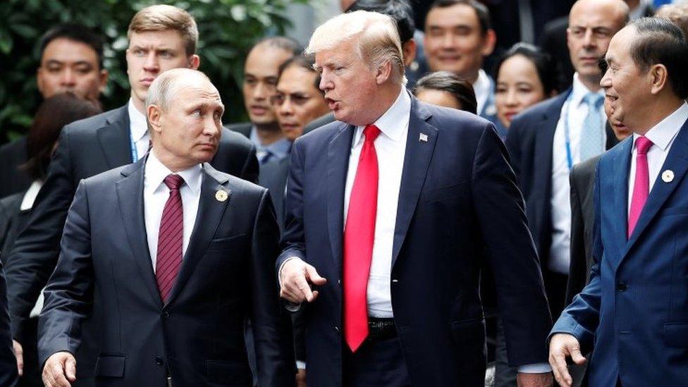 President Donald Trump and Russia"s President Vladimir Putin talk as Vietnam's President Tran Dai Quang (R) looks on, during the family photo session at the APEC Summit in Danang, Vietnam 11 November 2017.