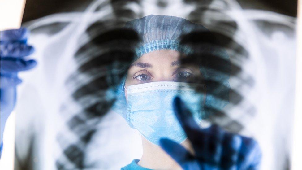 Doctor in medical mask looking at x-ray