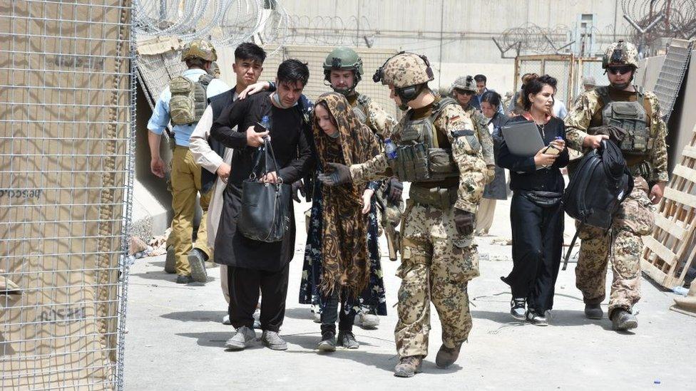 Soldiers help a women, fell due to high temperature at the Kabul International Airport