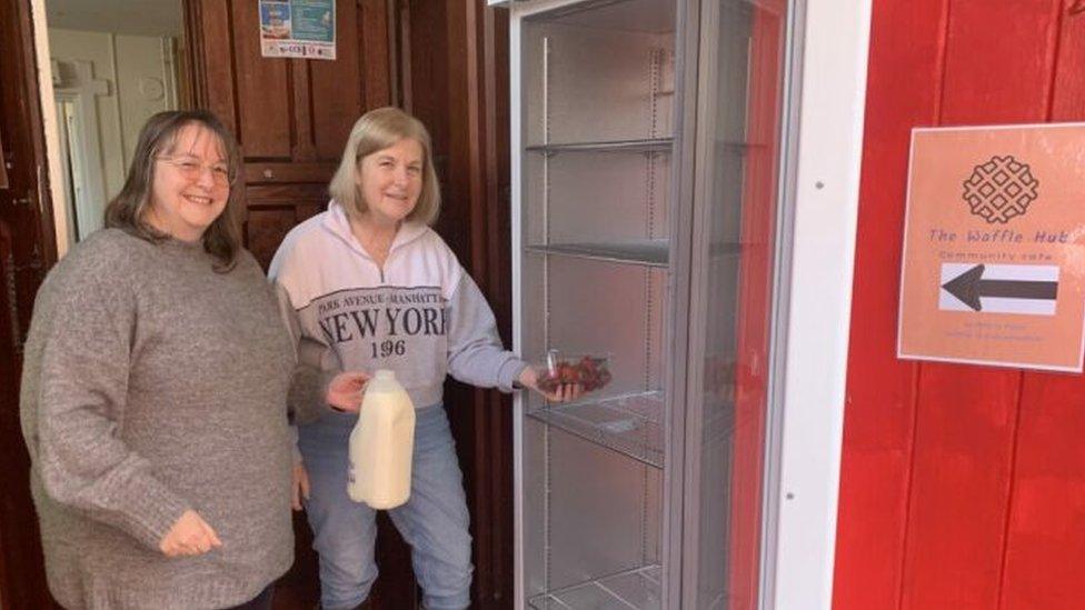 Two women stand next to the new fridge