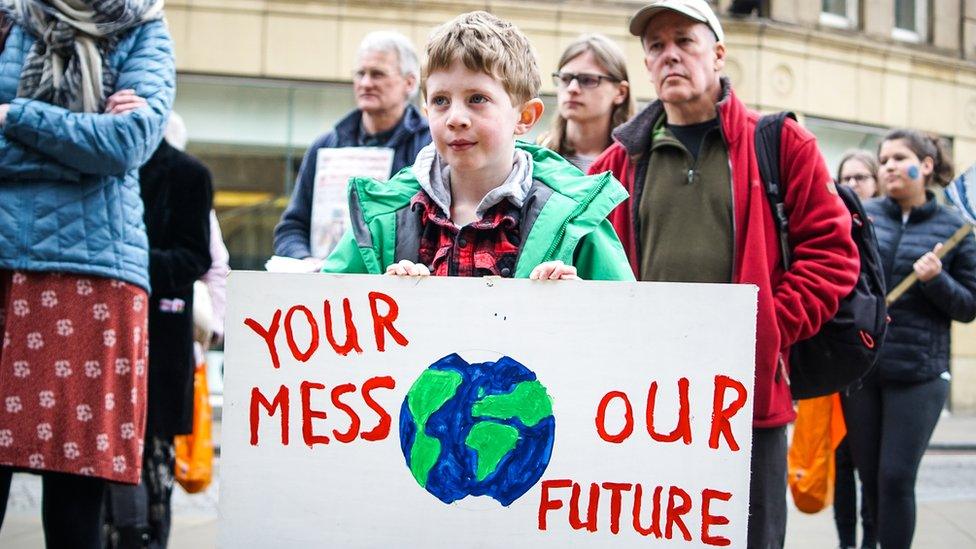 Boy-holds-up-a-banner-at-a-climate-change-protest.