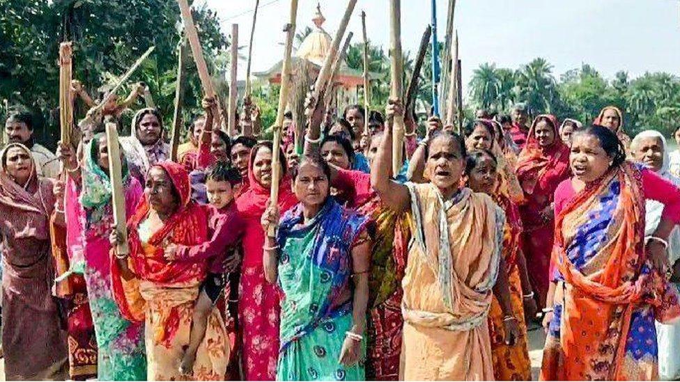 Women protesters at Sandeshkhali hold up sticks during their protest demanding the arrest of Shahjahan Sheikh