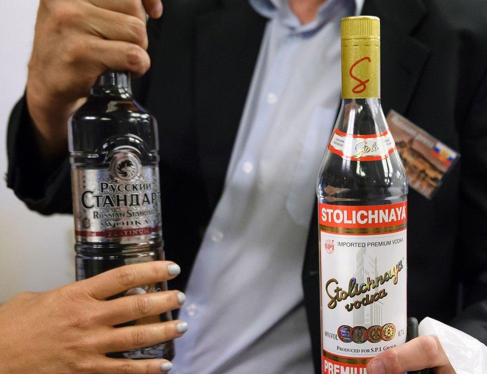 A journalist holds two bottles of vodka that Russian Foreign Minister Sergei Lavrov delivered to waiting journalists after meetings to discuss the Syrian crisis went late into the evening on 9 September 2016, in Geneva.