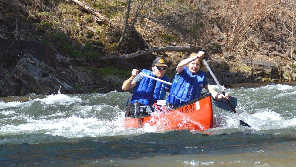 Students manoeuvre a canoe on a river