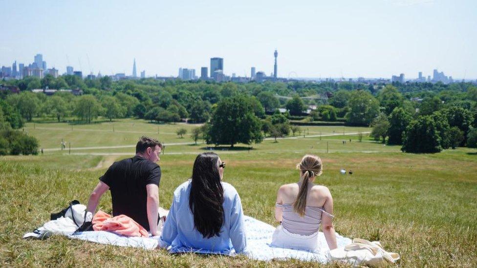 People sitting in the sun on Primrose Hill, London