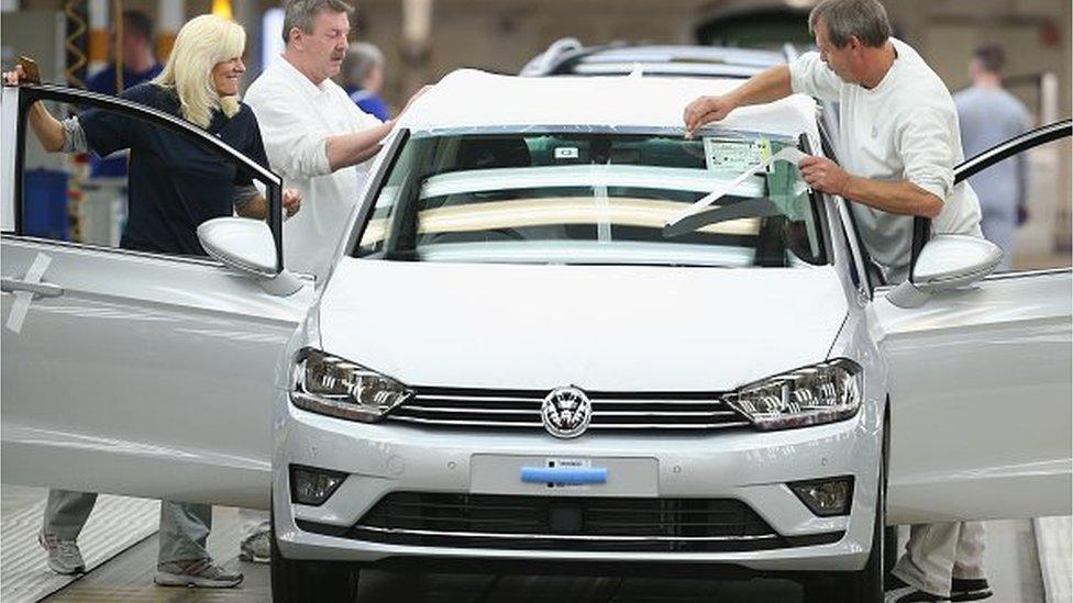 Workers conduct final inspections and prepare finished Volkswagen cars for transport