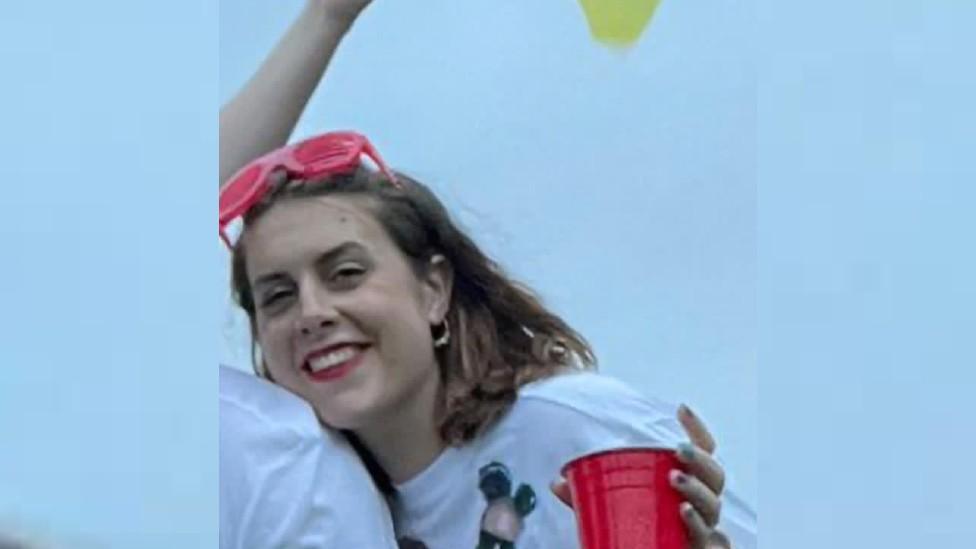 Victoria Watts wearing pink glasses on her head and holding a cup