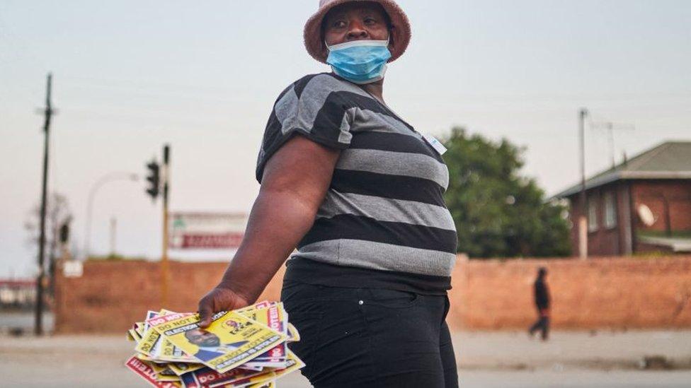 A woman holds flyers that read "Do not vote" as she goes to a polling station during Zimbabwe's presidential and legislative elections in Bulawayo on August 23, 2023