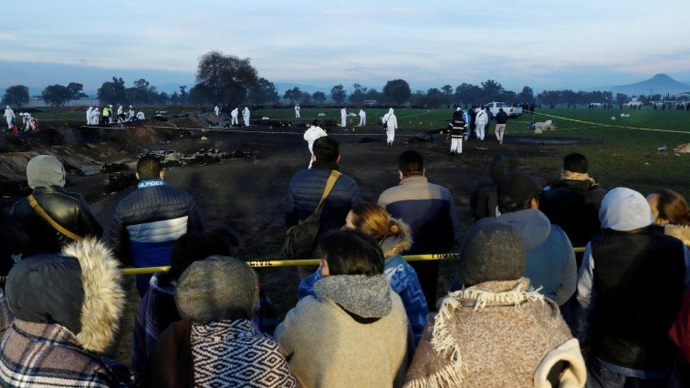 Relatives gather at the scene as forensic workers carry out inspections