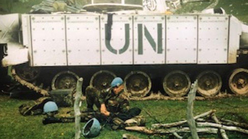 Shaun Pinner lying in front of a tank with UN written on the side