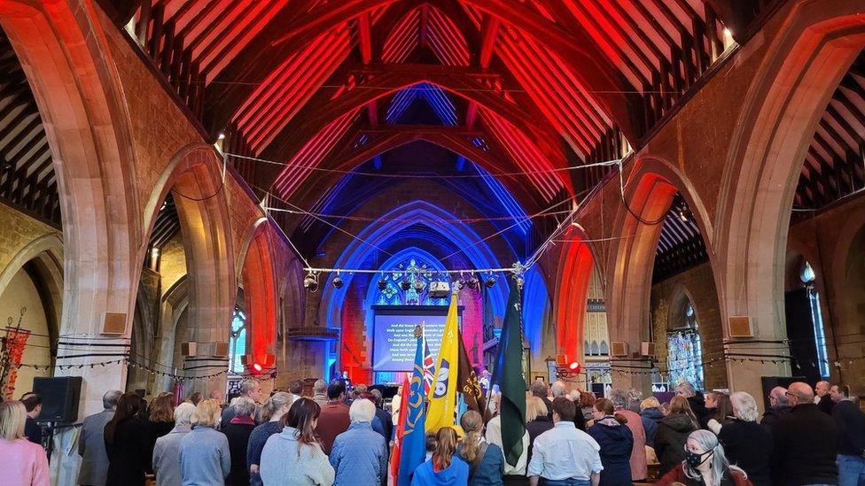 Standards raised in a church filled with coloured light