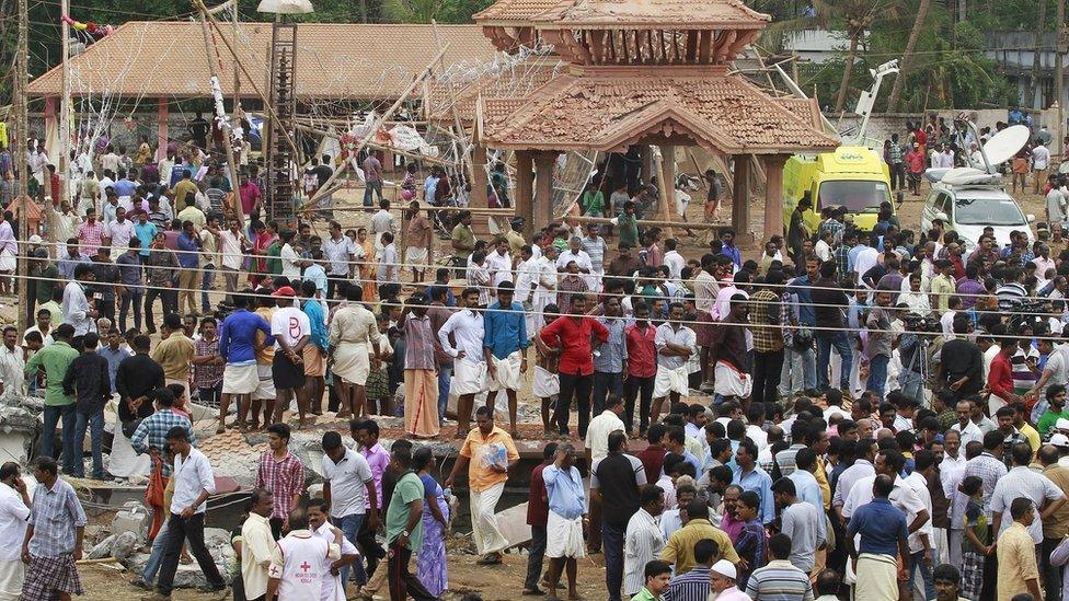 People gather inside the compound of a temple after a fire broke out at a temple in Kollam in the southern state of Kerala