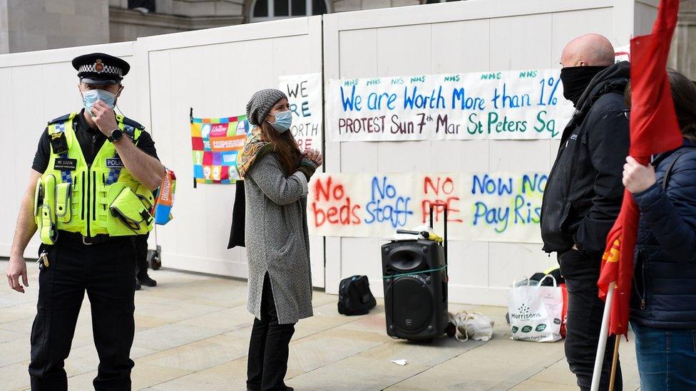 Policeman and protesters seen against backdrop of protest signs