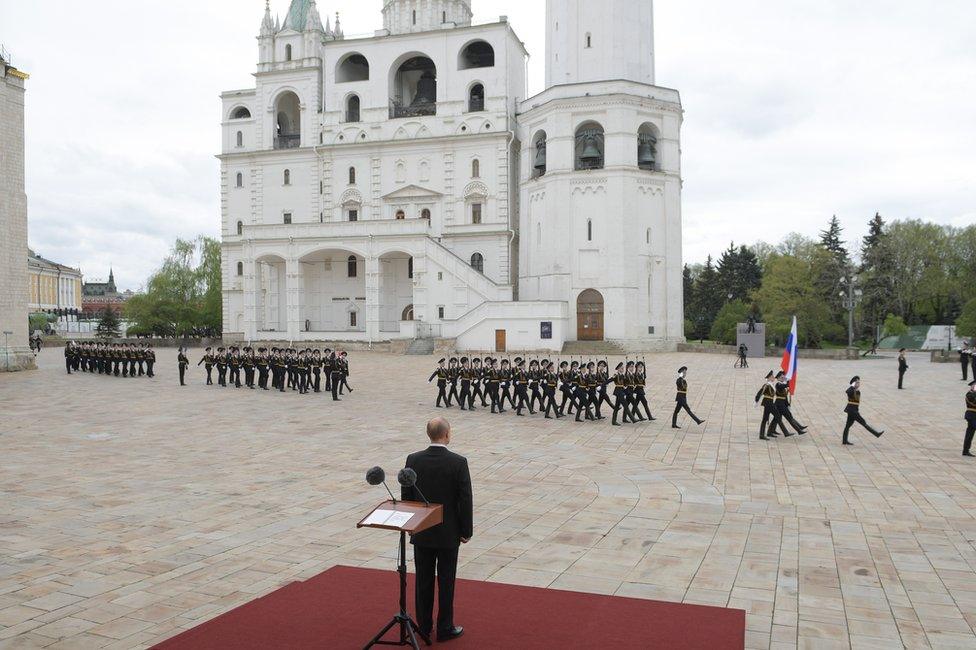 President Vladimir Putin stands watching a parade of soldiers in Moscow, Russia