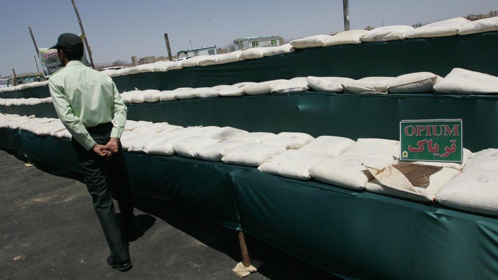 Image shows an Iranian policeman guarding 3,000kg (6,600lb) of opium seized from drug smugglers.