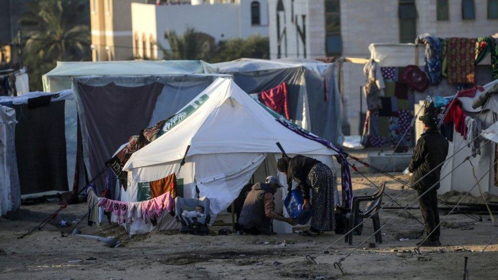 Palestinians who fled from the northern Gaza Strip, sit outside their shelters in Deir Al Balah, southern Gaza Strip, 16 January 2024.