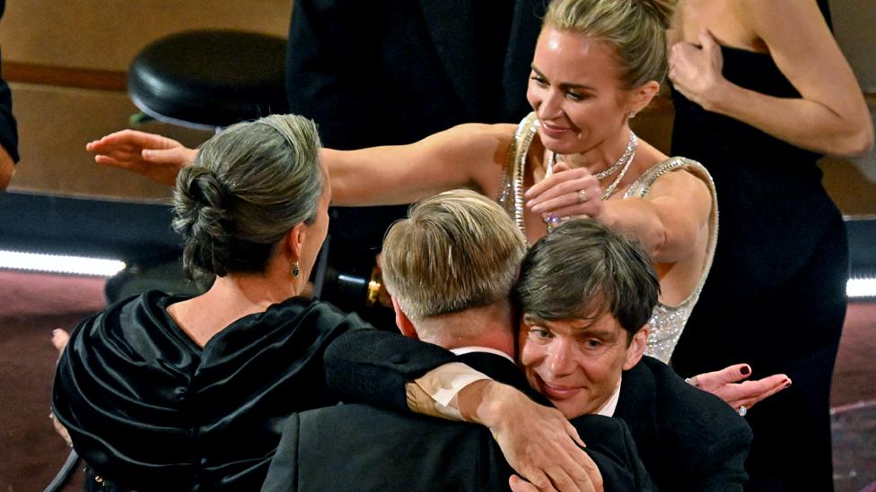 Cillian Murphy (2-R) embraces Christopher Nolan (2-L) as Emily Blunt (R) reaches for Emma Thomas (L) after the film Oppenheimer won the Oscar for Best Picture