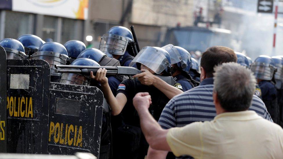 Policeman aims a weapon during a demonstration against a possible change in the law to allow for presidential re-election in front of the Congress building in Asuncion, Paraguay, March 31, 2017