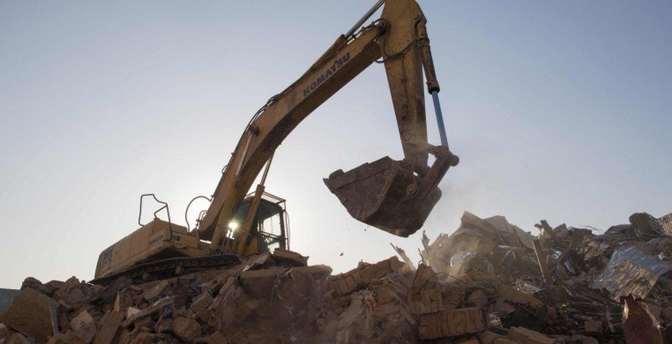 A bulldozer clears debris from buildings demolished by authorities in a migrant housing area on the outskirts of Beijing.